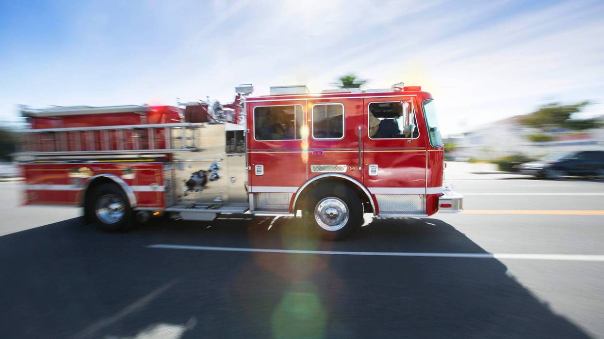 Fire engine drives along residential street during the daytime.