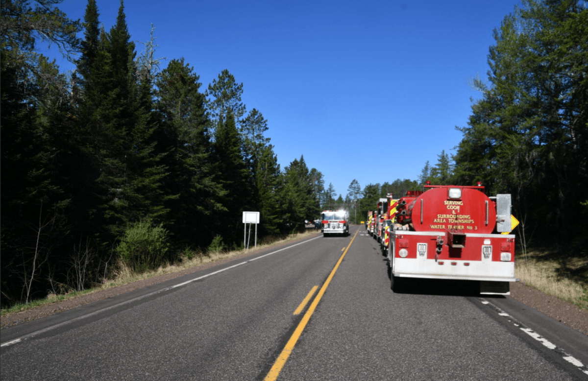 Fire trucks stage along a county highway in northern Minnesota for the Camp House Fire.