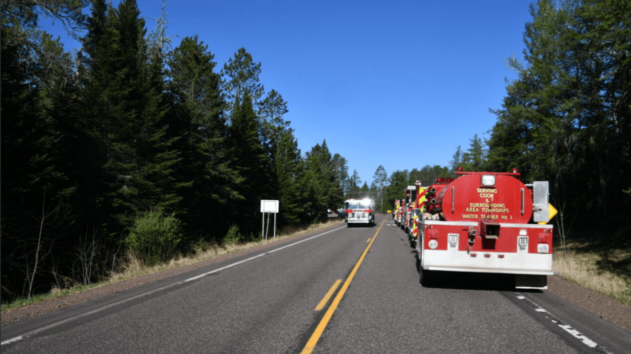 Fire trucks stage along a county highway in northern Minnesota for the Camp House Fire.