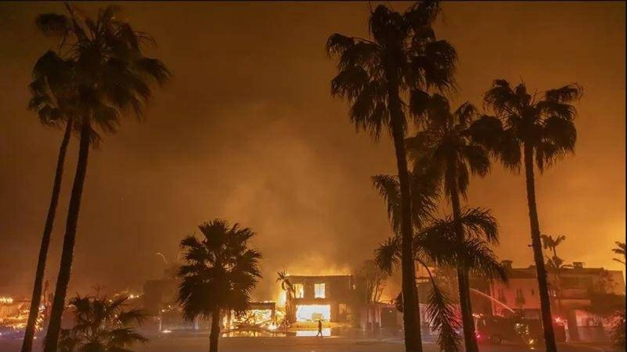 Firefighter watches flames from Palisades Fire burning homes