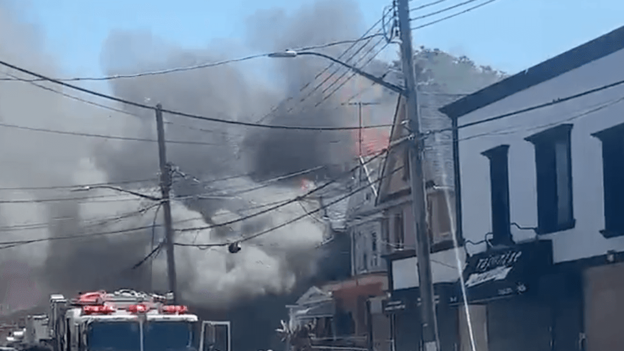 Firefighters are battling a five-alarm fire at a home in Queens that has reportedly spread to other buildings.
