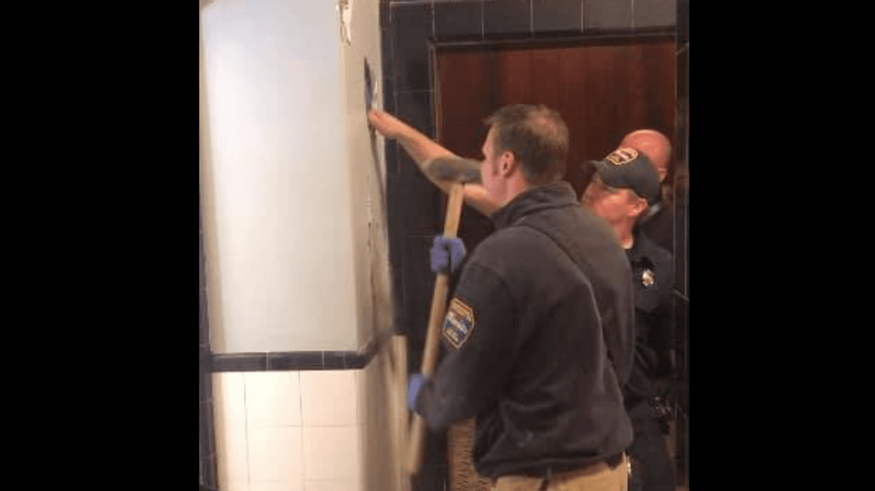 Firefighters breaking hole into wall
