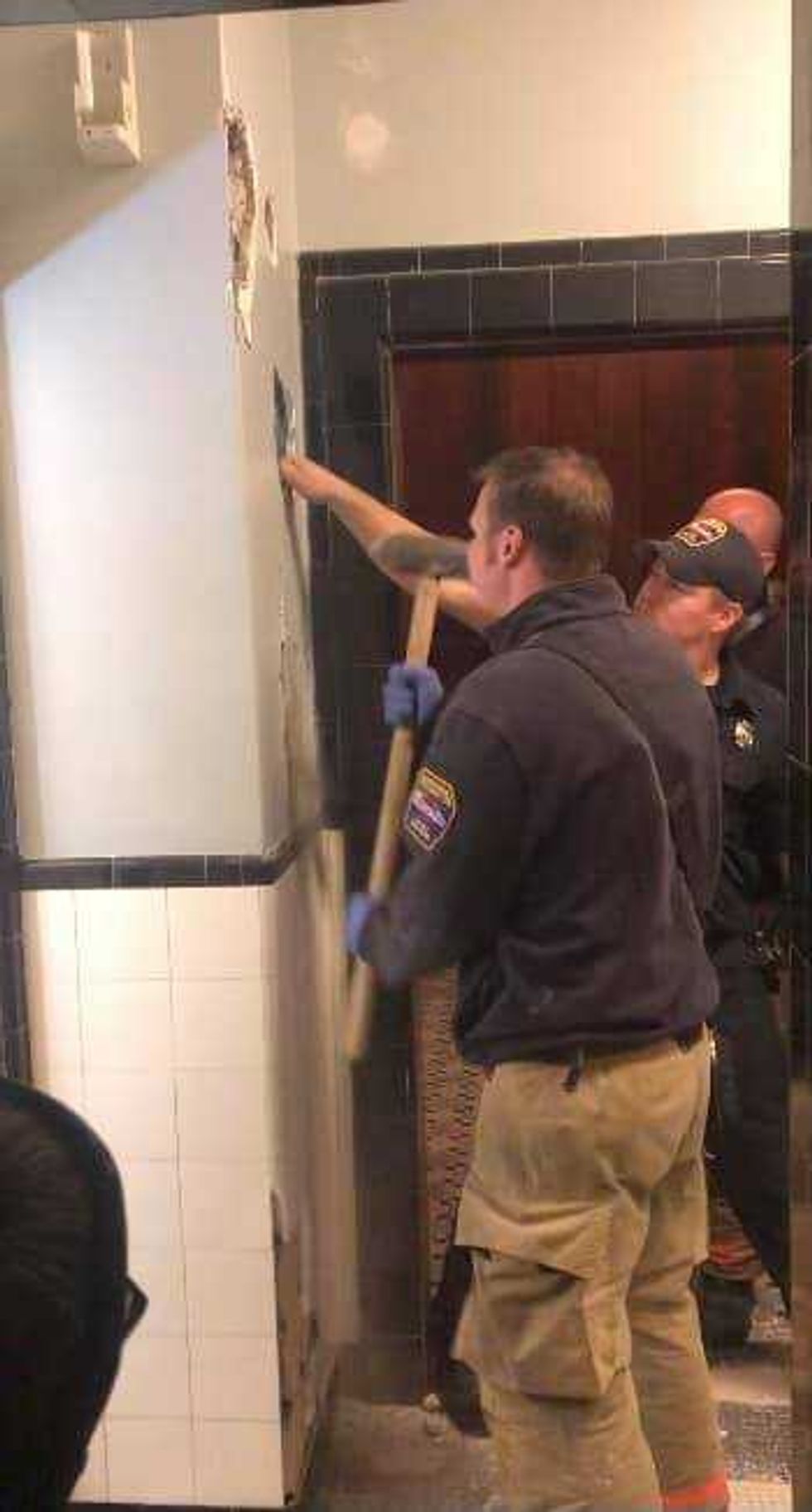 Firefighters pictured breaking hole into theater wall