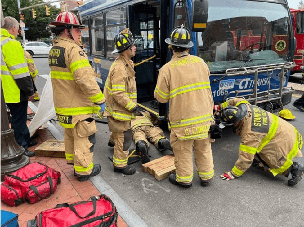 Firefighters rescuing woman from underneath bus