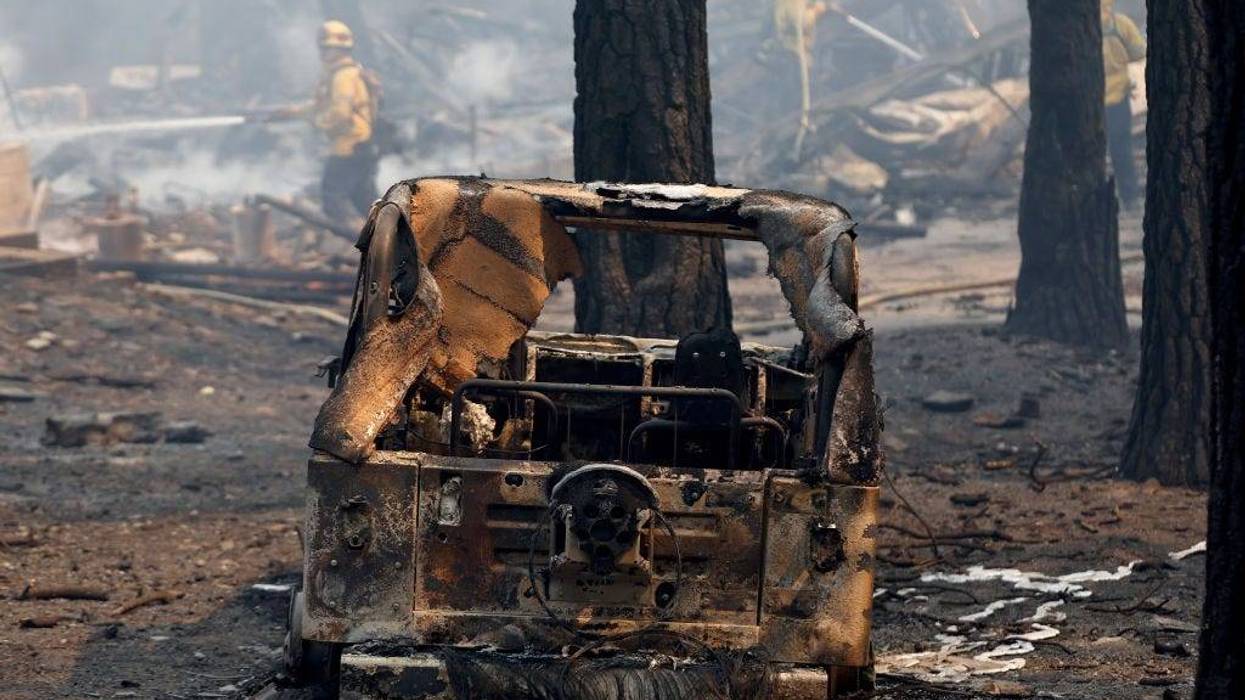 Firefighters spray down the remnants of a destroyed home near a destroyed vehicle (FOREGROUND) during the Bridge Fire which has now burned more than 47,000 acres in Angeles National Forest on September 11, 2024 in Wrightwood, California.