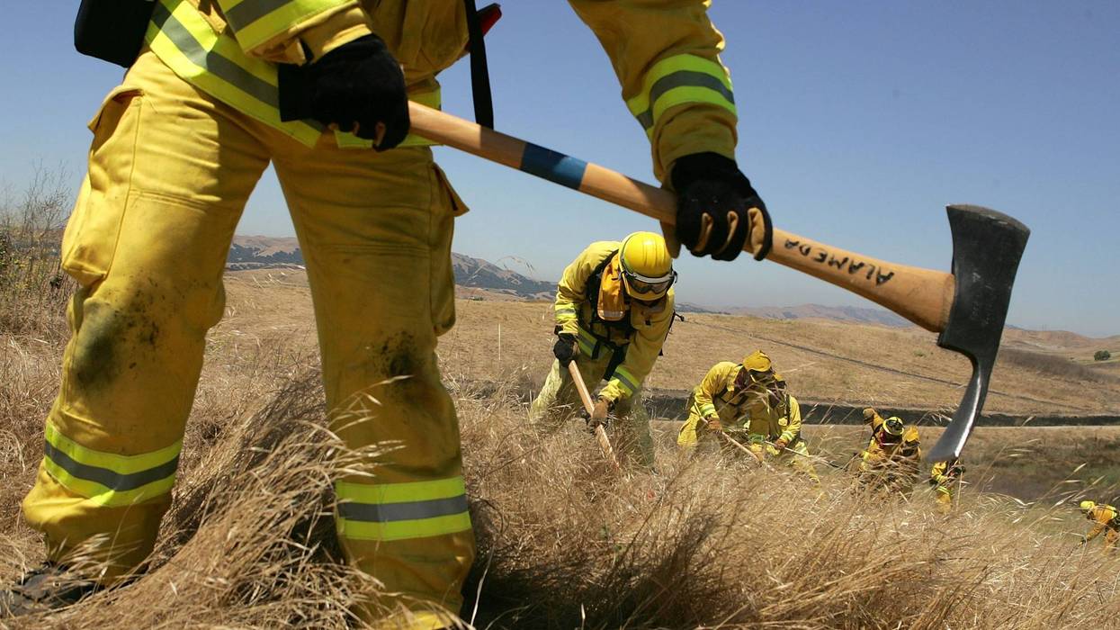 Firefighters use hand tools to create a fire line during a multi-agency wildfire drill in Dublin, California
