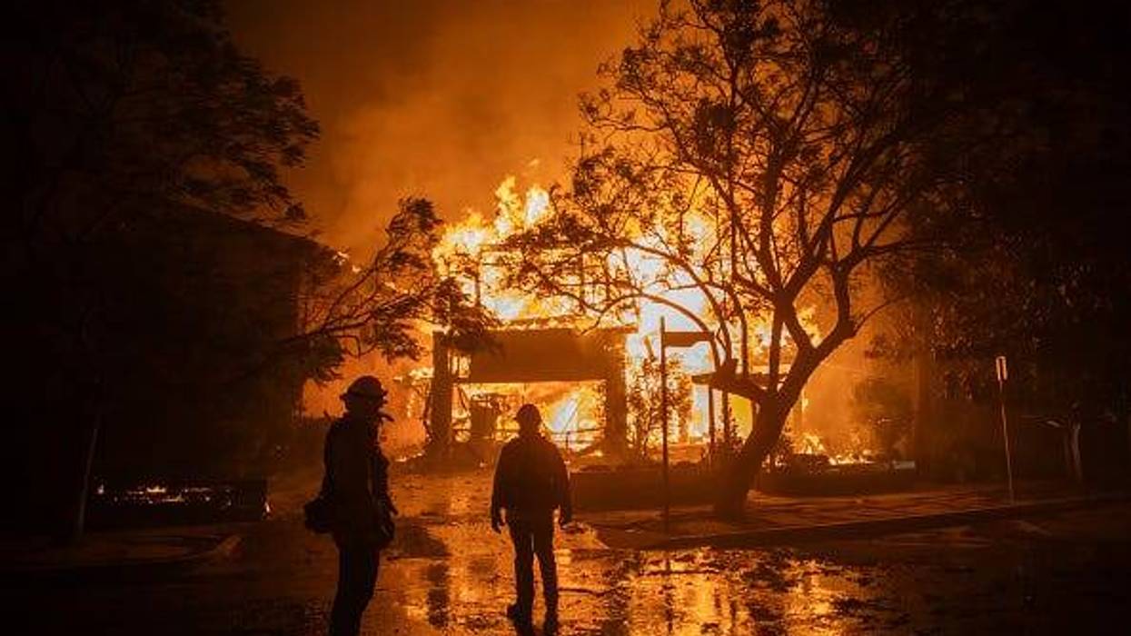 Firefighters watch the flames from the Palisades Fire burning a home during a powerful windstorm on January 8, 2025 in the Pacific Palisades neighborhood of Los Angeles, California.