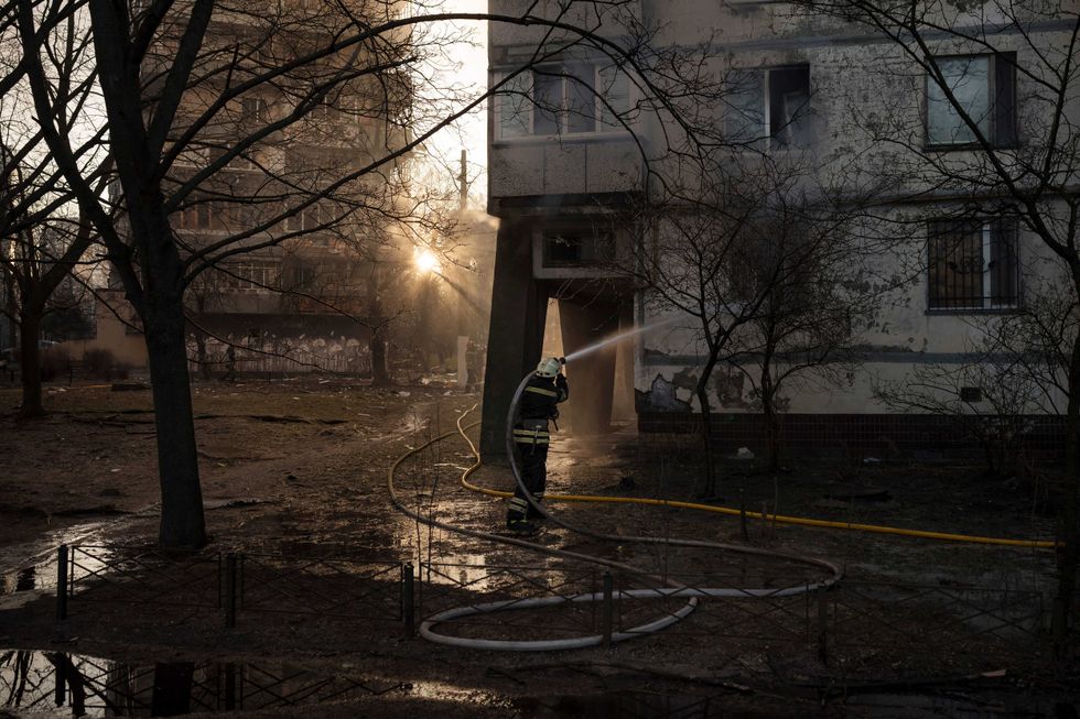 Firefighters work at the scene of an apartment building after it caught on fire from artillery shelling in Kyiv, Ukraine, Tuesday, March 15, 2022