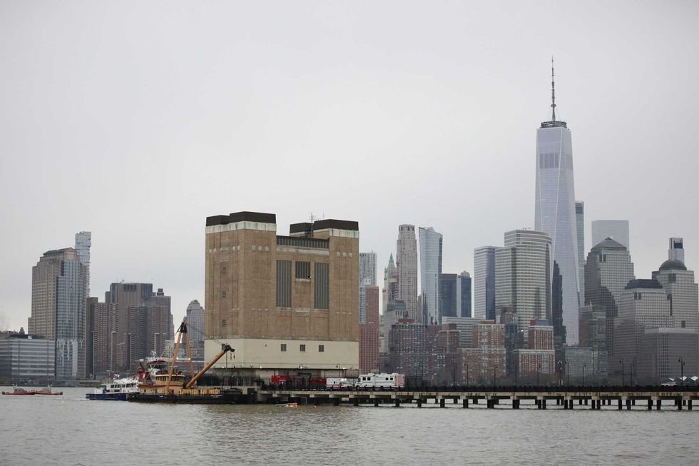 First responders are seen near the landing skids of a helicopter (C, in water) after it crashed into the Hudson River, in the Newport neighborhood of Jersey City, New Jersey, on April 10, 2025.