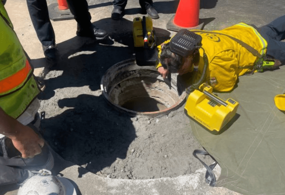 First responders look into the manhole.