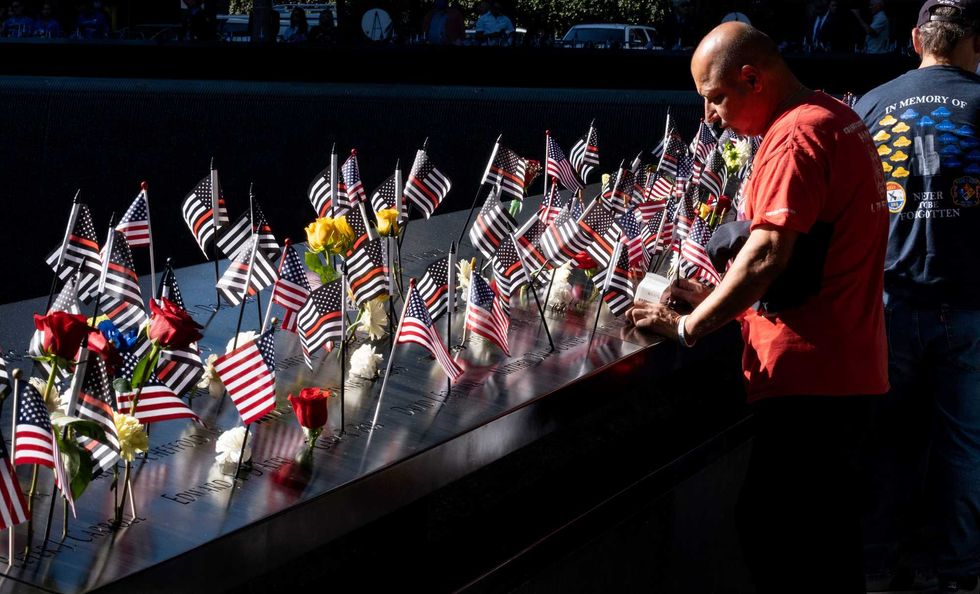 Flags and flowers adorn the names of the victims of the attacks of Sept. 11, 2001, during a ceremony at the 9/11 Memorial and Museum on September 11, 2021 in New York City