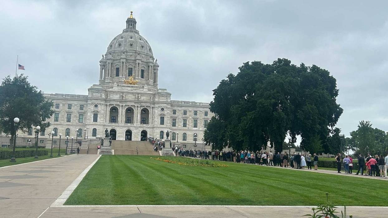Flags atop Minnesota state capitol building fly at half-staff as Melissa Hortman, her husband and family dog, all lie in state with mourners already lined up well outside the rotunda.