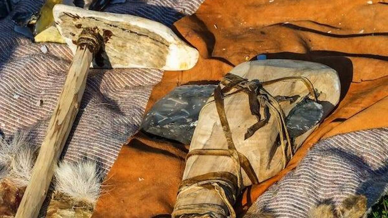 Flint axe and bone club resting on blankets
