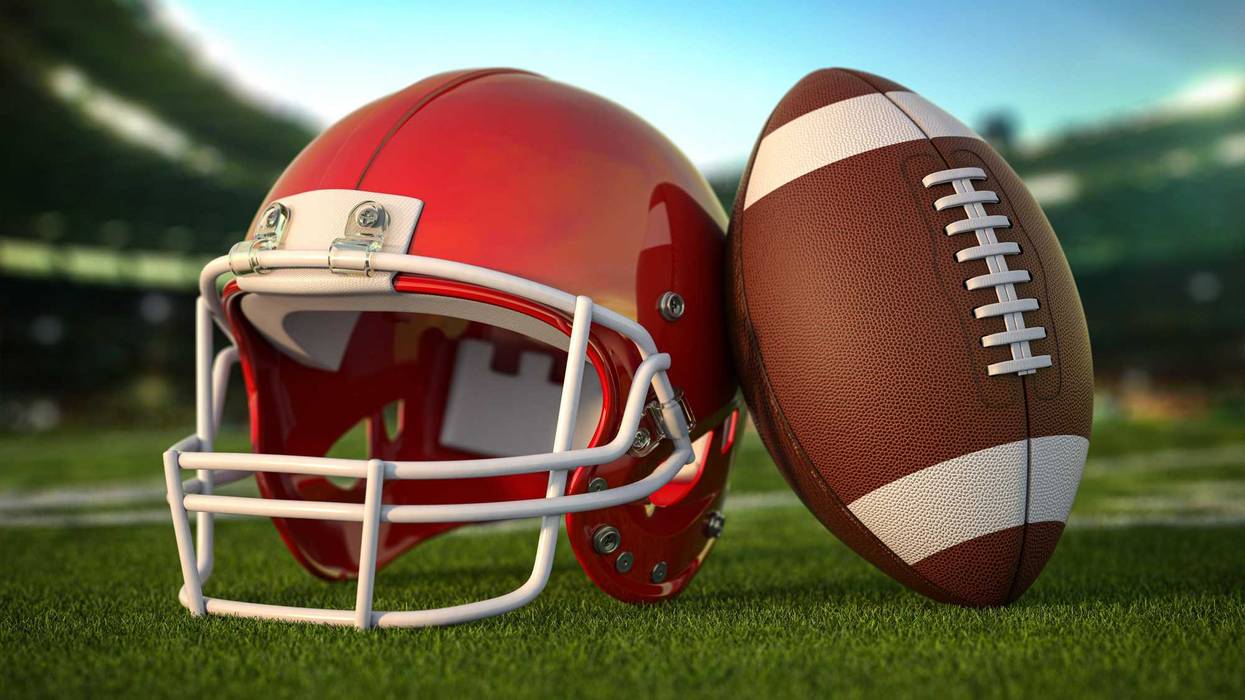 Football and helmet on the grass of football stadium