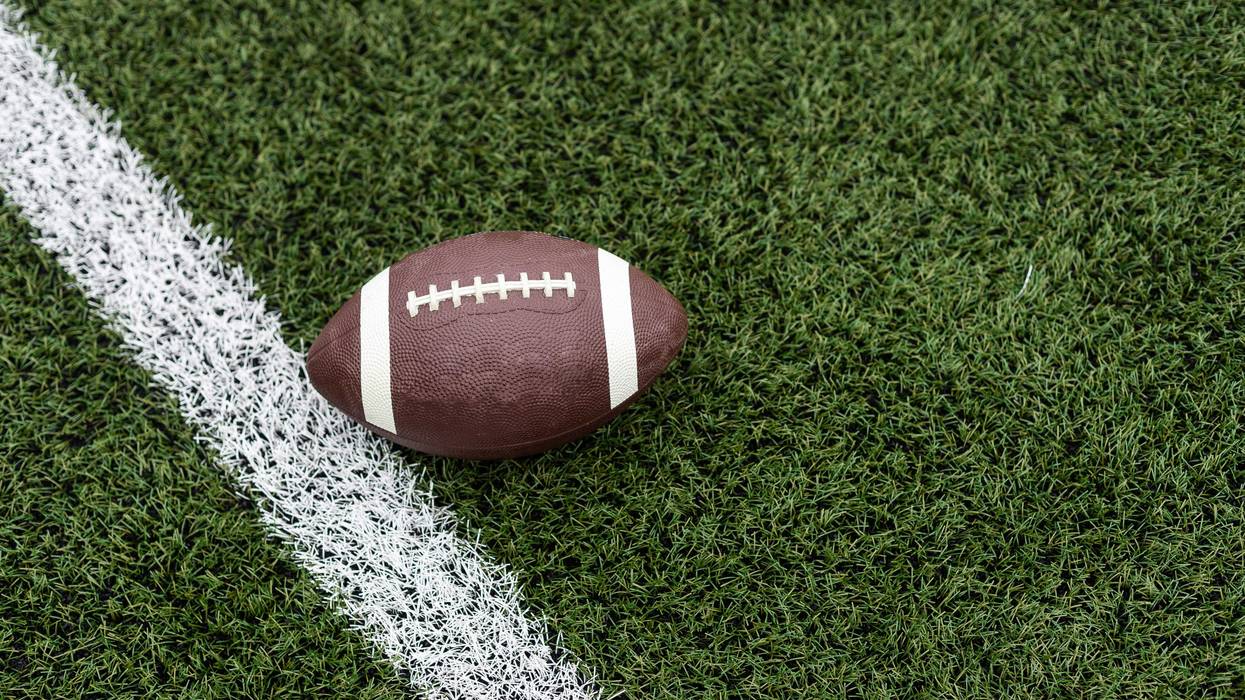 Football by a yard marker on a football field.