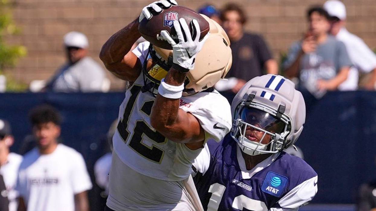 Football player in white catches pass, contested by a Cowboys defender in blue.