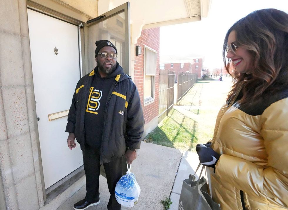 Former Detroit Lions Demetrious Johnson along with University of Missouri Athletic Director Desiree Reed-Francois, knock, on a door to deliver a Thanksgiving Day turkey and fixings at an apartment complex in St. Louis on Saturday, November 19, 2022. Over 3,000 turkeys were delivered to those of underprivileged households for Thanksgiving Day by the Demetrious Johnson Foundation.