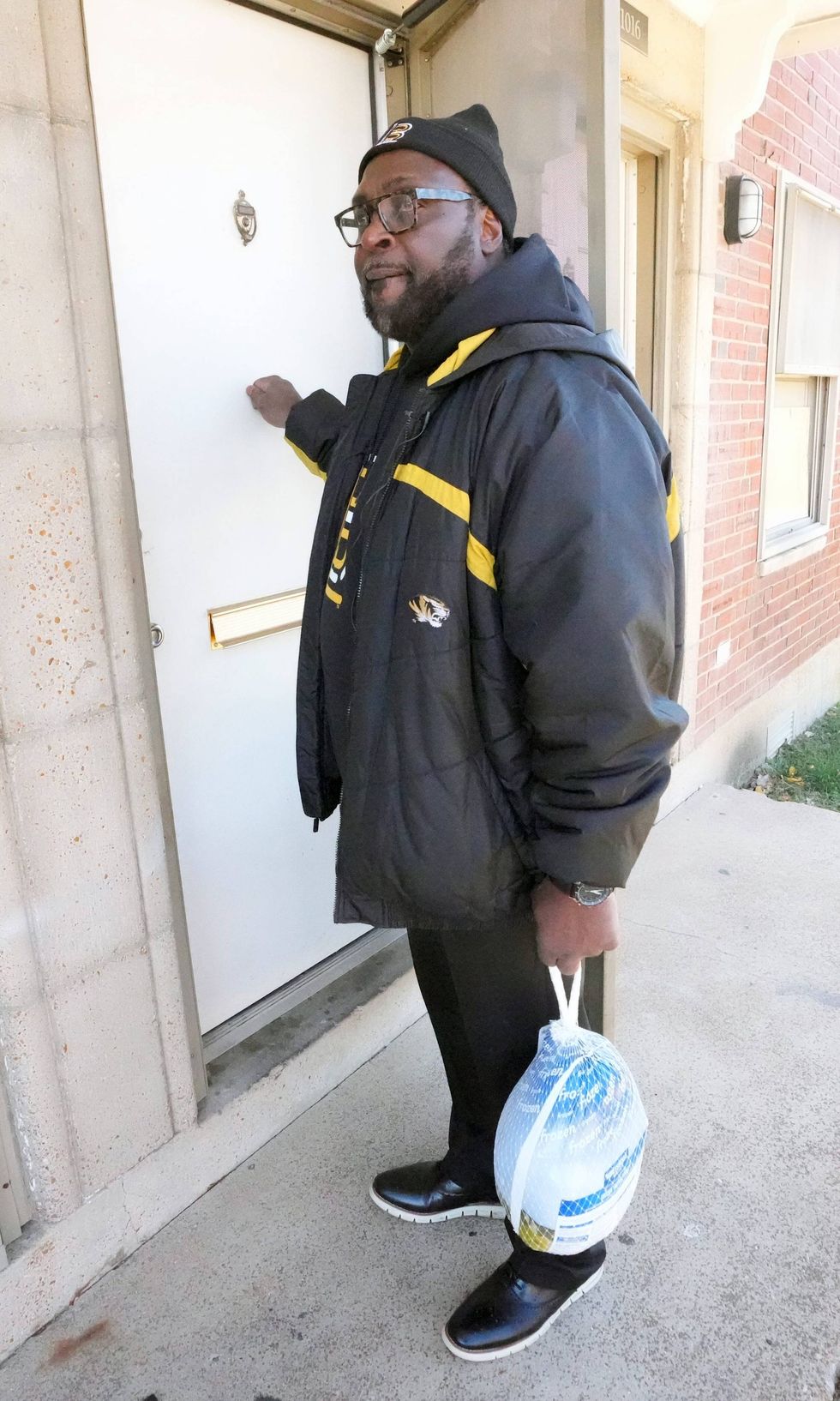 Former Detroit Lions Demetrious Johnson knocks on a door to deliver a Thanksgiving Day turkey and fixings at an apartment complex in St. Louis on Saturday, November 19, 2022. Over 3,000 turkeys were delivered to those of underprivileged households for Thanksgiving Day.