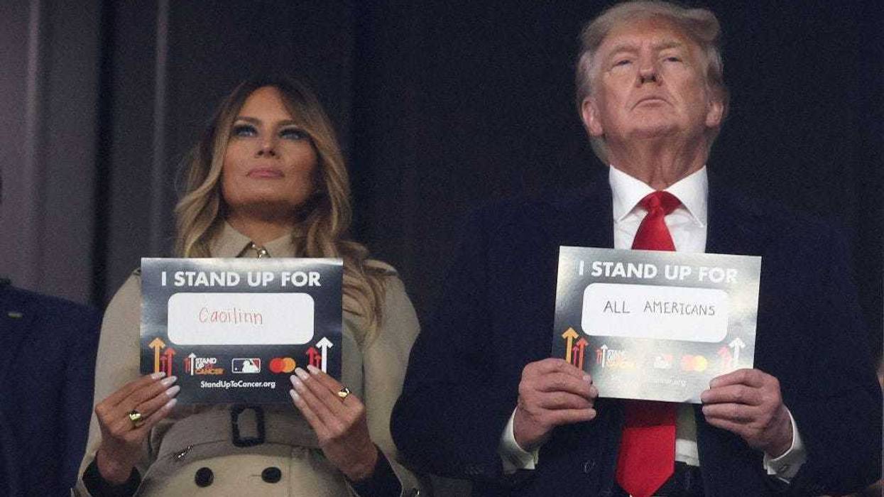 Former first lady and president of the United States Melania and Donald Trump hold up signs for "stand up to cancer" prior to the sixth inning in Game Four of the World Series between the Houston Astros and the Atlanta Braves Truist Park on October 30, 2021 in Atlanta, Georgia. (Photo by Elsa/Getty Images)