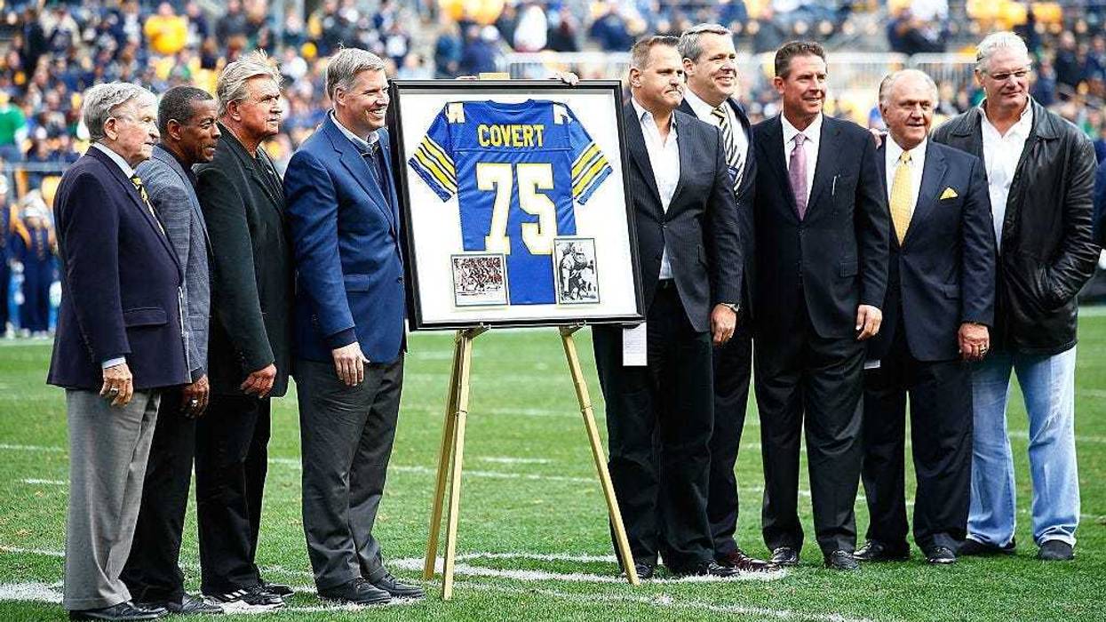 Former Pittsburgh Panthers player Jimbo Covert is surrounded by his former teammates after having his number retired at halftime between the Pittsburgh Panthers