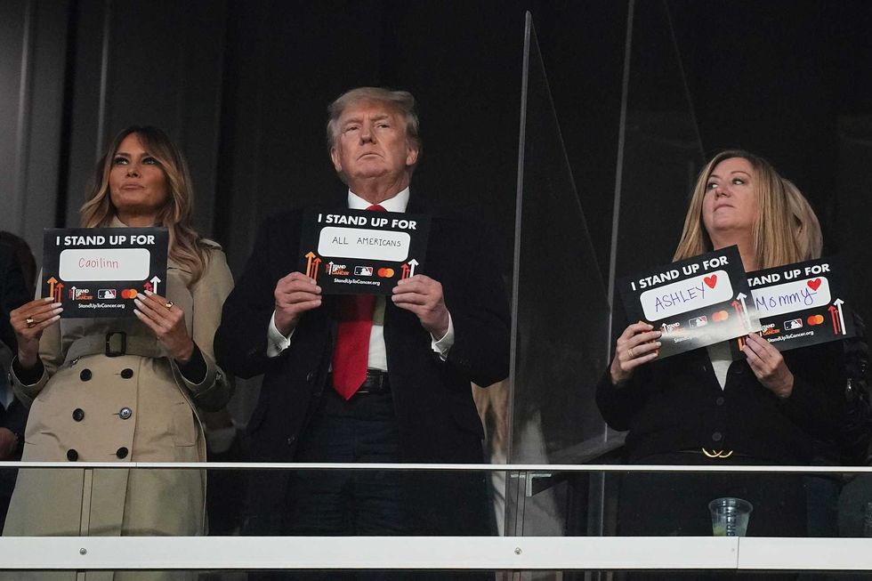Former President Donald Trump and his wife Melania participate in the "stand up for cancer" campaign during the fifth inning in Game 4 of baseball