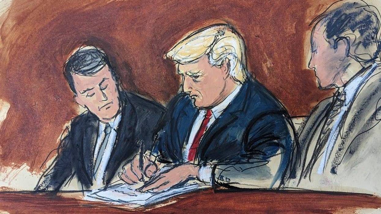 Former President Donald Trump, center, flanked by his defense attorneys, signs his bond in federal court, Tuesday, June 13, 2023, in Miami. Trump plead not guilty to federal charges that he illegally kept classified documents at his Florida estate.