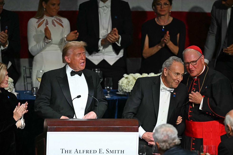 Former President Donald Trump (L) speaks alongside US Senate Majority Leader Chuck Schumer (C) and Archbishop of New York Timothy M. Dolan (R) during the 79th Annual Alfred E. Smith Memorial Foundation Dinner at the Hilton Midtown in New York, October 17, 2024