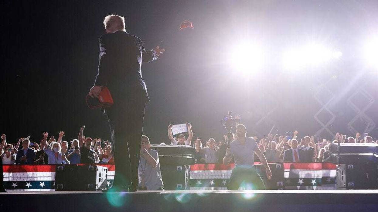 Former President Donald Trump tosses a MAGA hat to a supporter at the "Save America" rally on August 121, 2021, in Cullman, Alabama.