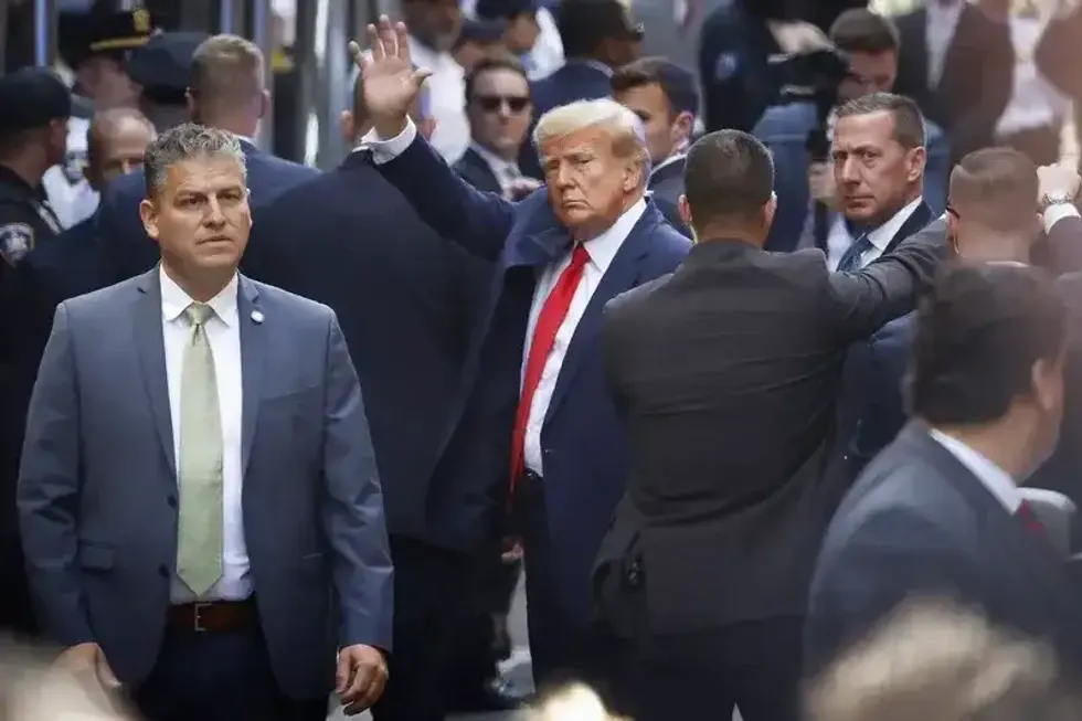 Former President Donald Trump waves as he arrives at Manhattan Criminal Court for his arraignment hearing on April 4, 2023.