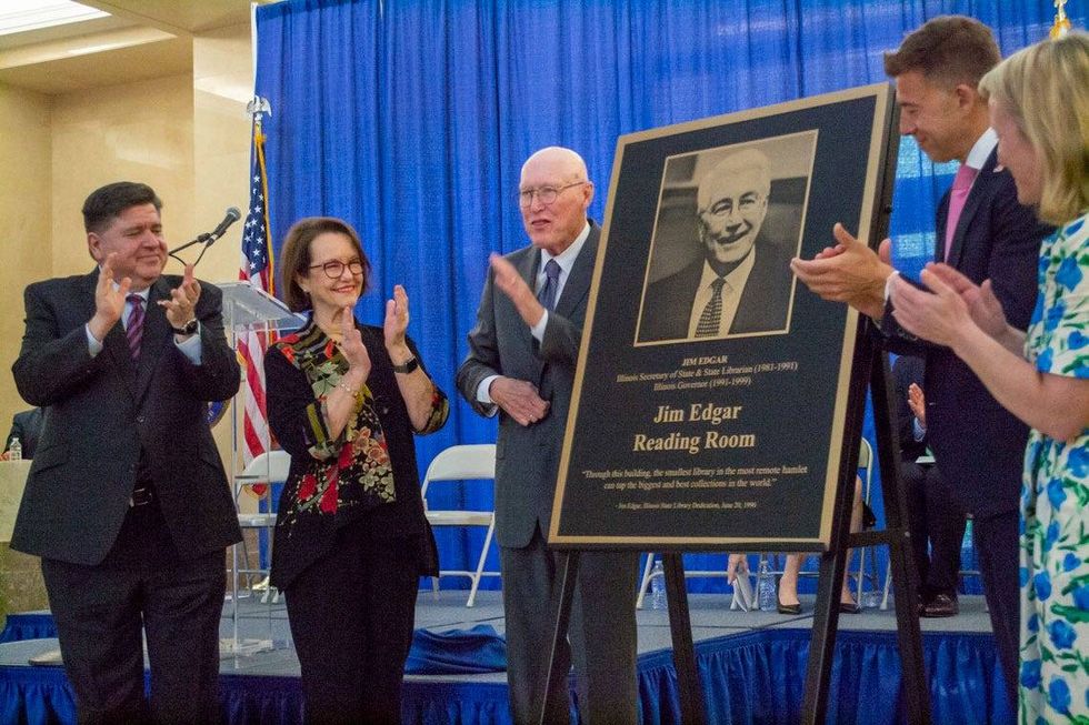 Former Republican Gov. Jim Edgar, center, unveils a plaque honoring his name on the reading room at the Illinois State Library. Also pictured are Gov. JB Pritzker, Edgar