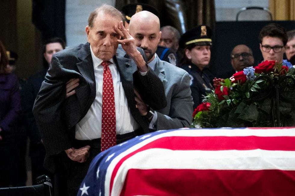 Former Senator Bob Dole stands up and salutes the casket of the late former President George H.W. Bush