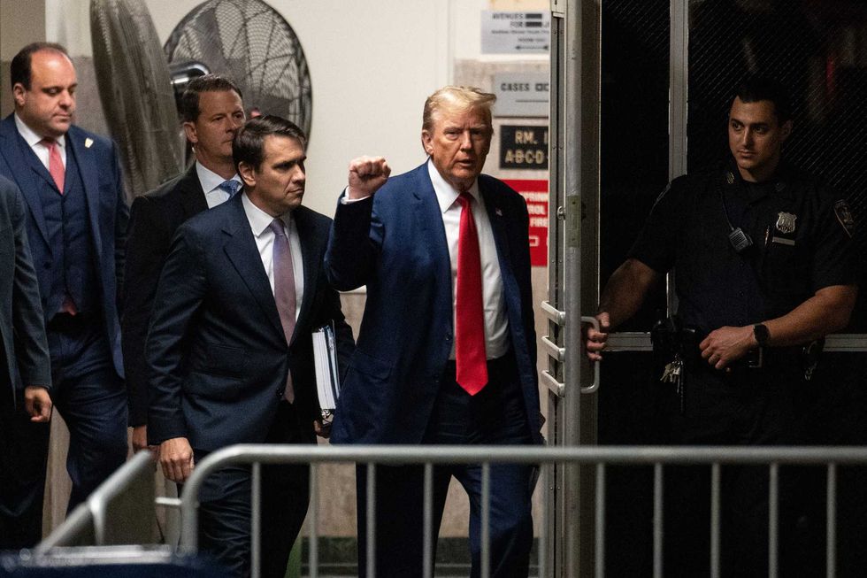 Former U.S. President Donald Trump raises his fist as he and attorney Todd Blanche return after a break in the day