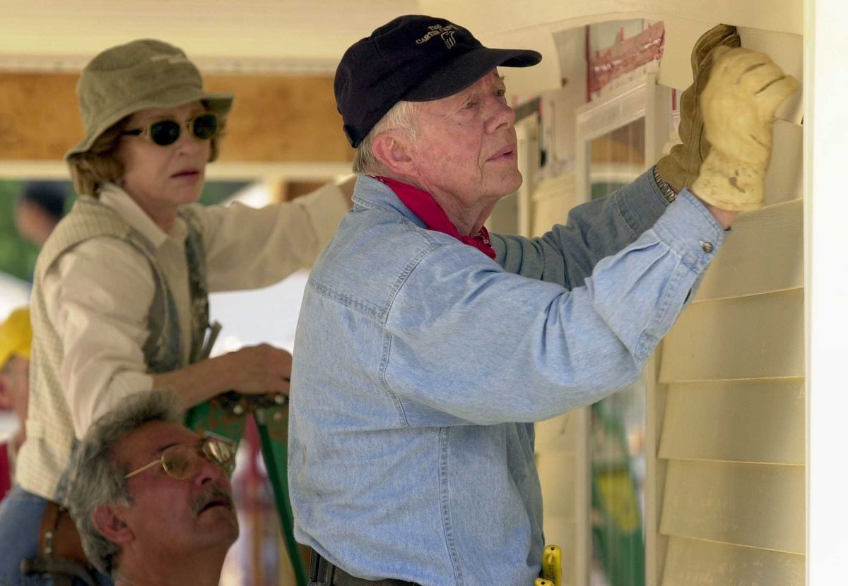 Former US President Jimmy Carter and former First Lady Rosalyn Carter attach siding to the front of a Habitat for Humanity home being built June 10, 2003 in LaGrange, Georgia.