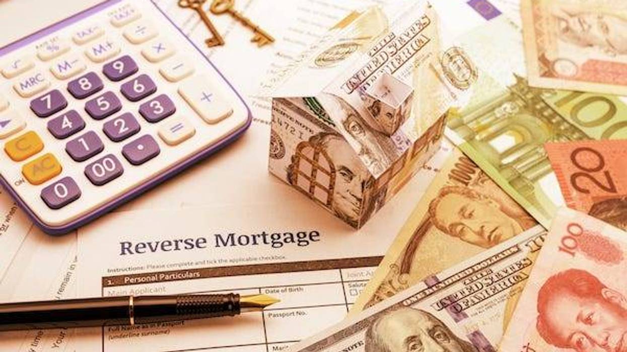 Fountain pen, brass keys, a calculator, a dollar paper house and a blank reverse mortgage form with banknotes