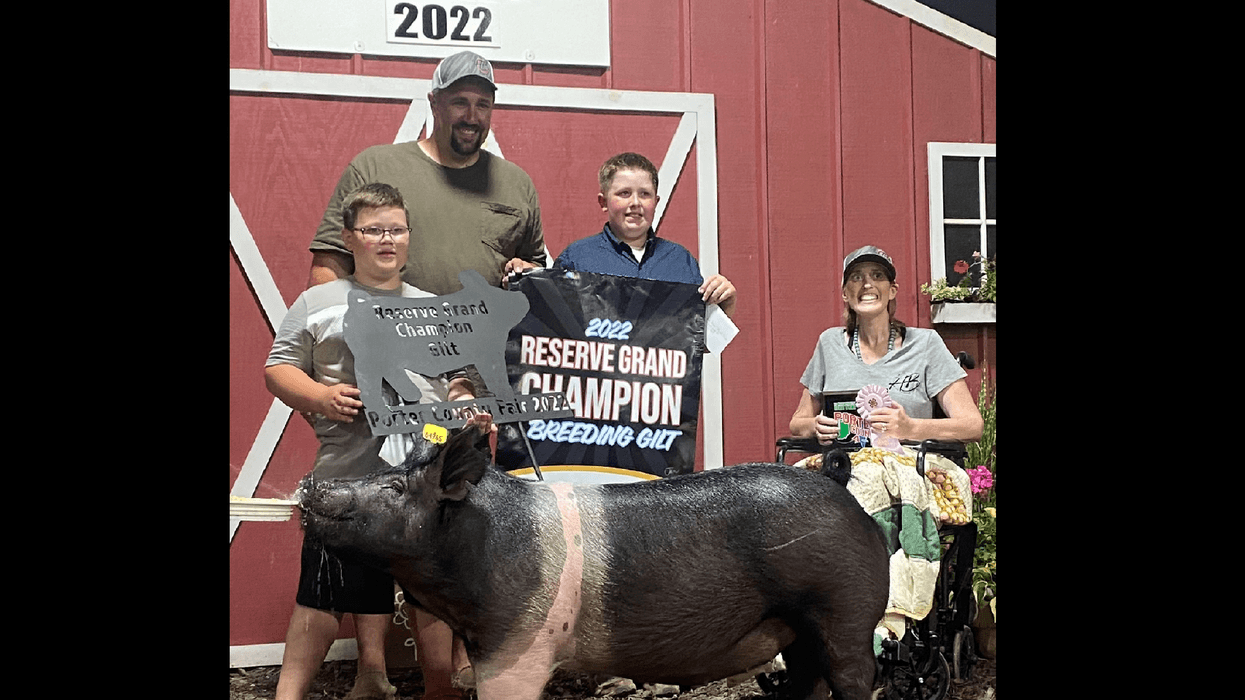 Four people and a pig stand with champion banners at the Porter County Fair