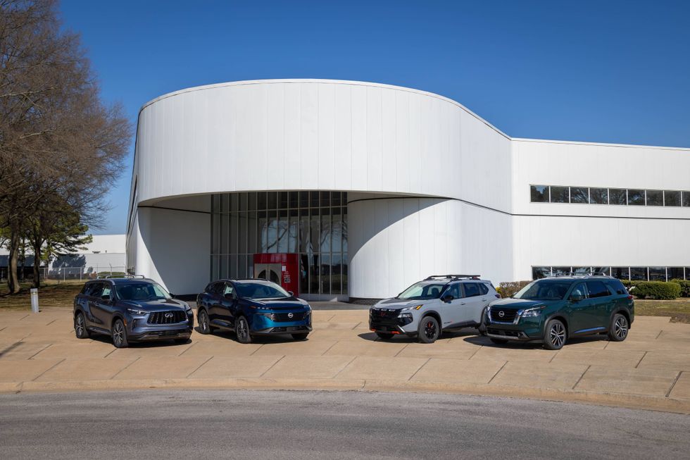 Four SUVs are parked in front of a modern white cylindrical building, under a clear blue sky. The scene conveys a sense of technology and innovation.