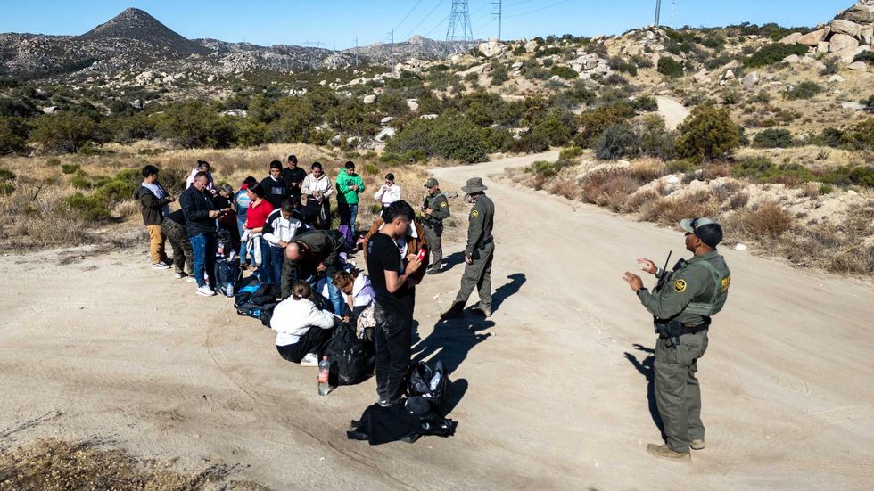 From an aerial view U.S. Border Patrol agents gather a group of Colombian asylum seekers after they crossed over from Mexico on September 22, 2024 near Jacumba Hot Springs, California. Immigrant border crossings remained low months after the Biden Administration