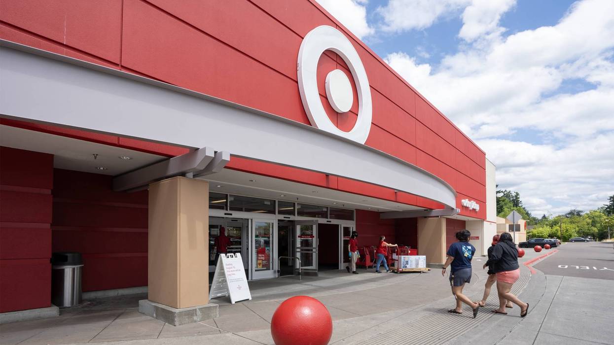Front view of a red Target store with its bullseye logo, customers, and a red sphere bollard.