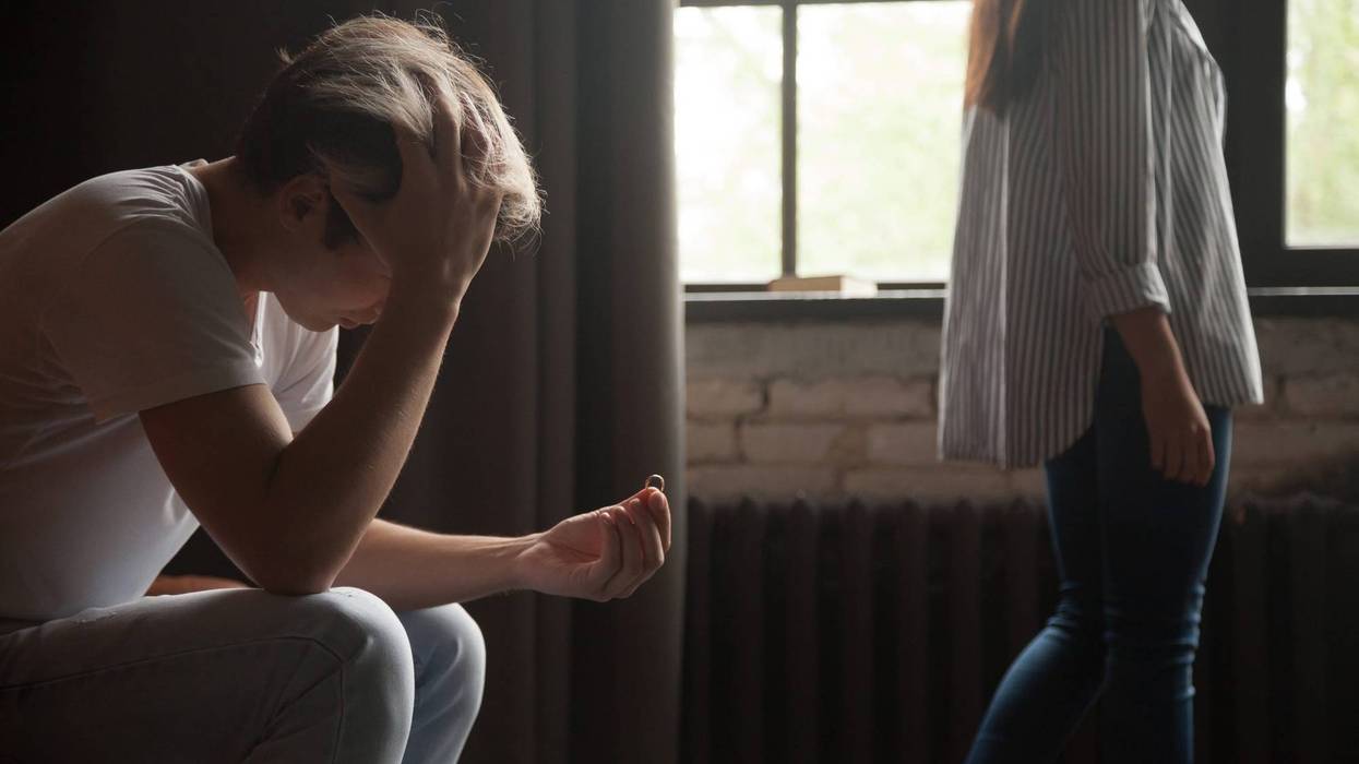 Frustrated man holding wedding ring, couple breaking up divorce concept