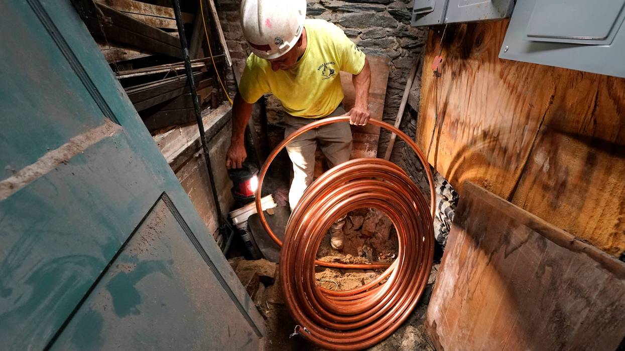 George Philbin, of Boyle & Fogarty Construction, works to feed a new copper residential water supply line, after removing an old lead residential water supply line, in the basement of a home where service was getting upgraded, June 29, 2023, in Providence, R.I.