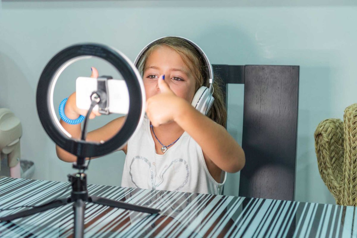 Girl making ok symbol with both hands to her followers while recording with her cell phone for her videos on social networks.