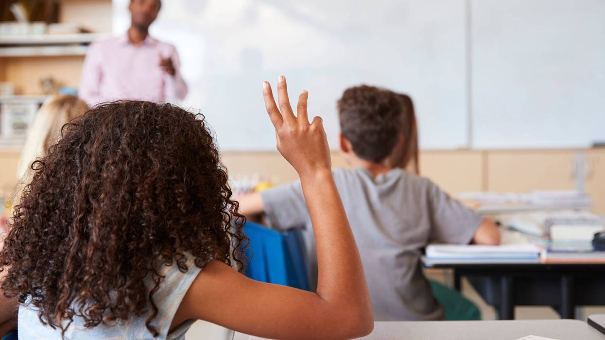 Girl raising hand to answer in an elementary school class