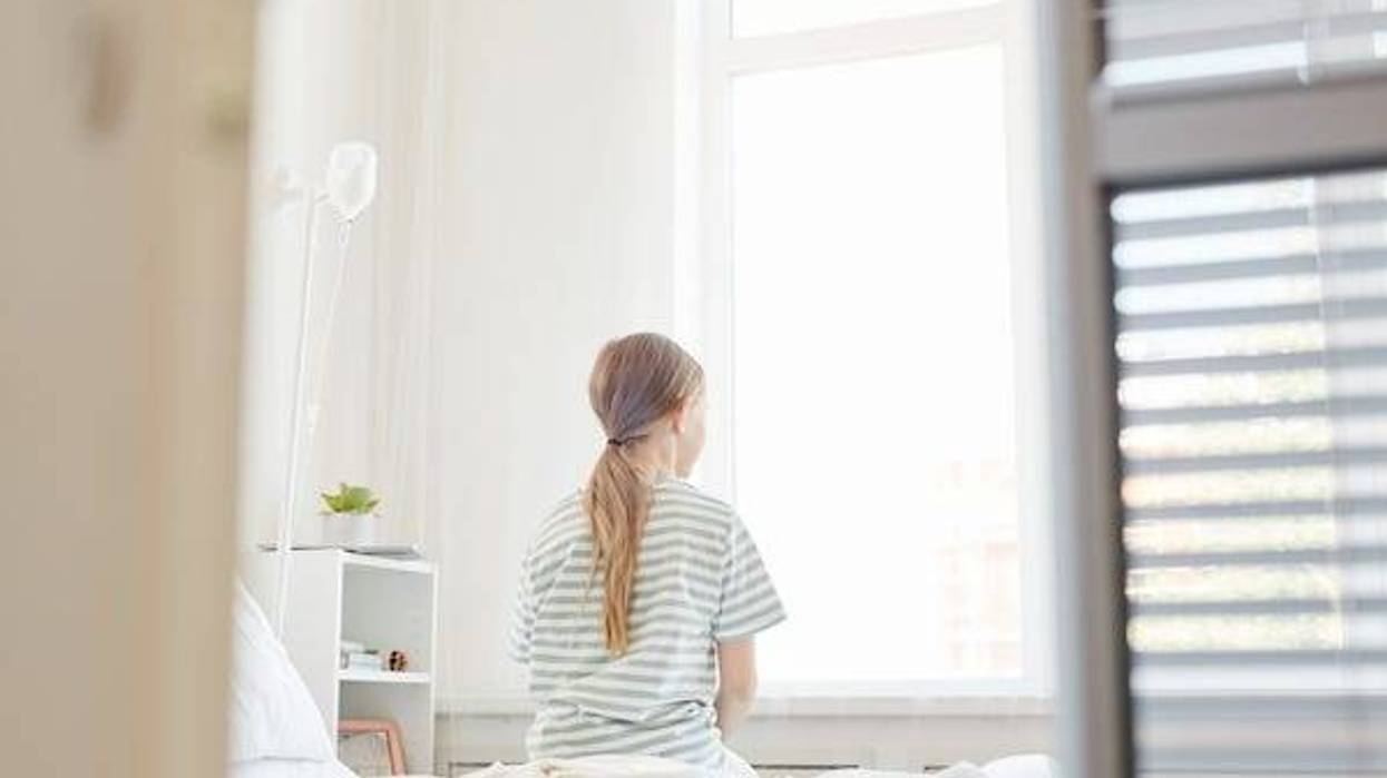 Girl sitting on hospital bed staring out window