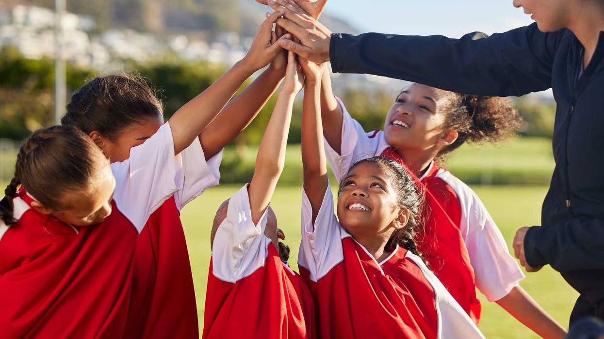 Girls on a team in a huddle raising their arms