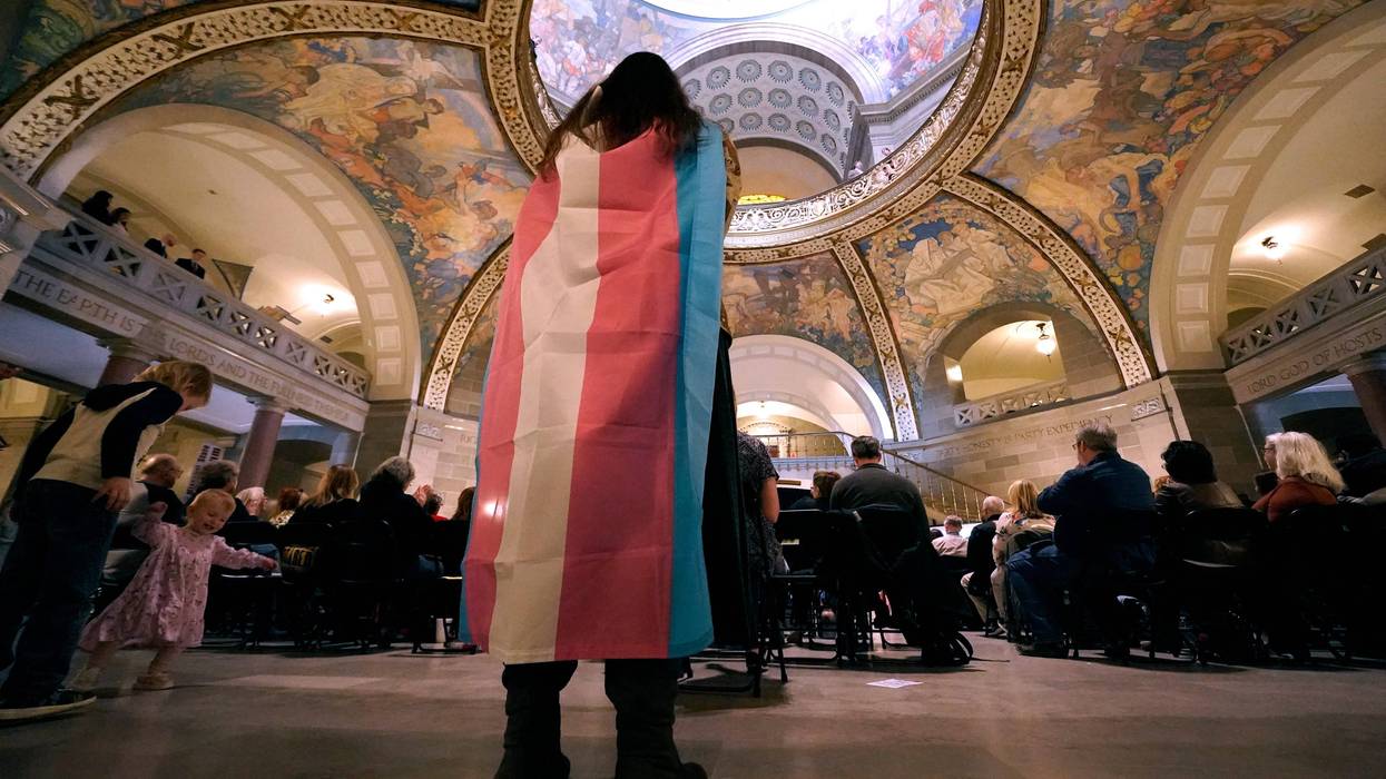 Glenda Starke wears a transgender flag as a counter protest during a rally in favor of a ban on gender-affirming health care legislation, March 20, 2023, at the Missouri Statehouse in Jefferson City, Mo. A Missouri judge said Friday, Aug. 25, that a law banning gender-affirming treatments for minors can take effect. St. Louis Circuit Judge Steven Ohmer ruled that the law will kick in Monday, Aug. 28, as previously scheduled.