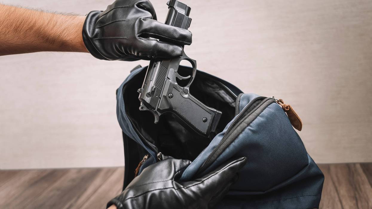 Gloved hands pulling gun out of luggage