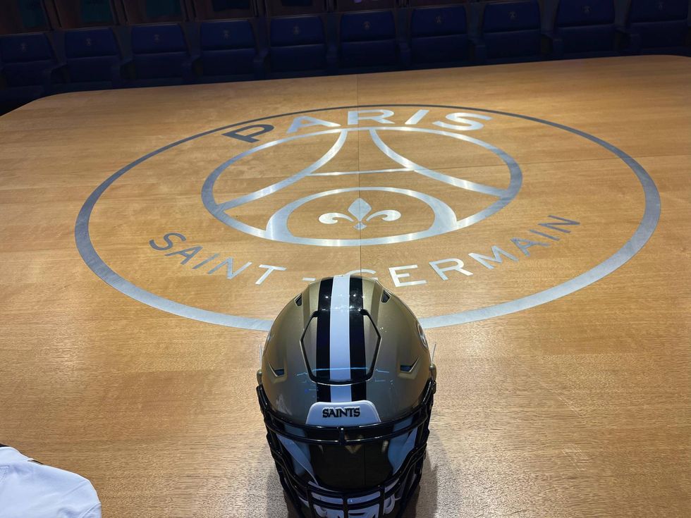 Gold and black Saints football helmet on a wooden floor featuring the Paris Saint-Germain logo.