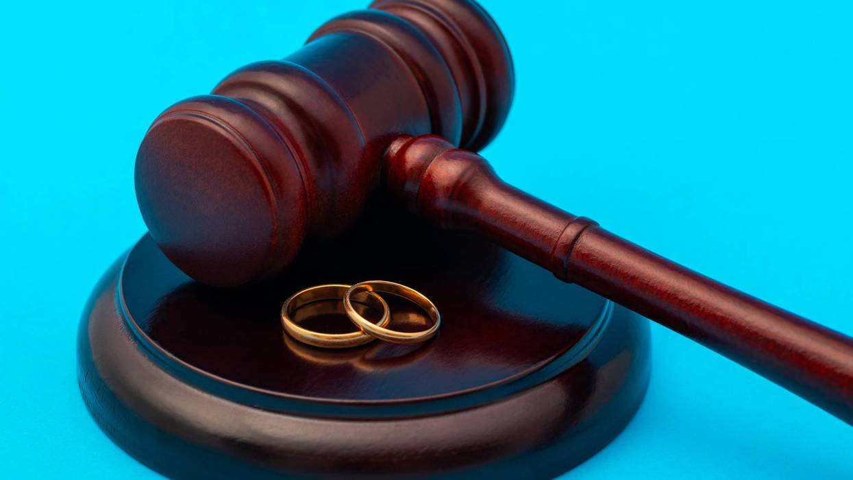 Golden wedding rings and hammer of fate on blue background