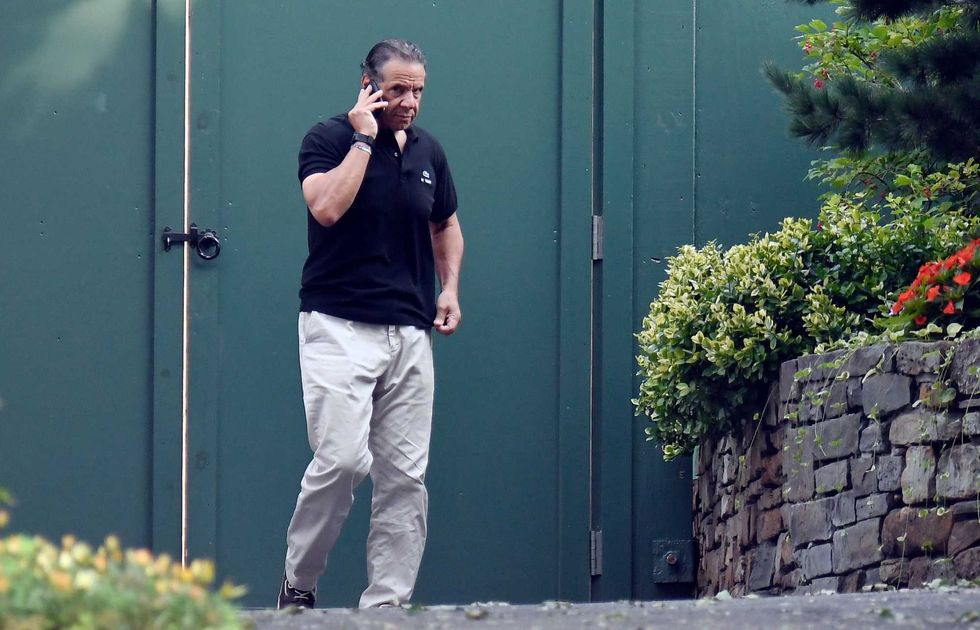 Gov. Andrew Cuomo talks on the phone while walking with his dog Captain at the New York state Executive Mansion, Saturday, Aug. 7, 2021, in Albany, N.Y