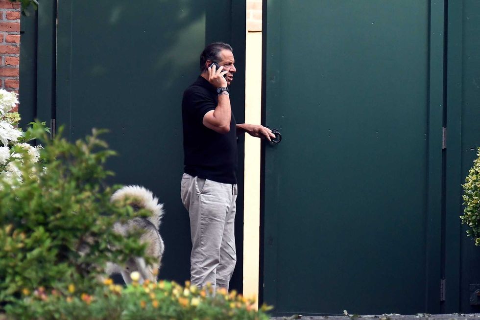 Gov. Andrew Cuomo talks on the phone while walking with his dog Captain at the New York state Executive Mansion, Saturday, Aug. 7, 2021, in Albany, N.Y